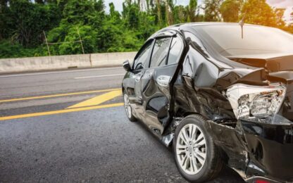 The side of a black sedan is shown crumpled after a car accident. 