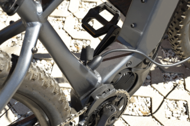 Electric mountain bike is charging, with the plug inserted to recharge the battery.