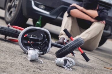 scared and stressed desperate drunken driver and bottle of beer in front of automobile crash car with child bike after traffic accident in city road